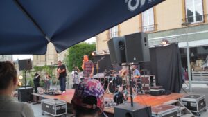Un groupe de musicien sur scène à Évreux. Un chanteur, un batteur et un guitariste.